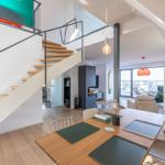 Essbereich mit Tisch, Stühlen und Tischdecken. Hintergrund zeigt Wohnbereich und Treppe.