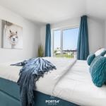 Schlafzimmer mit Bett, Fenster und Wandbild.