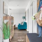 Eingangsbereich mit Holzschrank, Pflanze und blauem Sofa im Hintergrund.
