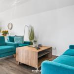 Wohnzimmer mit türkisfarbenen Sofas, Holz Couchtisch und Pflanzen.