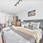 Schlafzimmer mit Bett, Nachttisch, Fernseher und Essbereich.