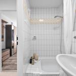 Badezimmer mit Dusche, Waschbecken und Blick in Schlafzimmer