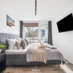 Schlafzimmer mit Bett, TV und Balkonansicht