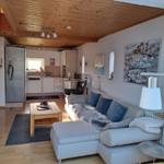 Living area with sofa, coffee table, and kitchen in the background.
