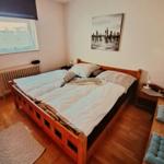Double bed with wooden frame, wall art, and nightstand