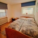 Bedroom with double bed, two windows, and wooden furniture.