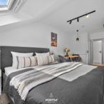 Schlafzimmer mit Dachfenster, Bett, Tisch und Stühlen.