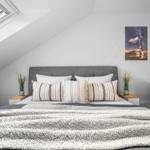Schlafzimmer mit Dachschrägen, Bett, Nachttischen und Fenster.