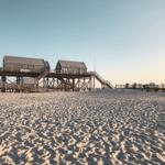 Zwei hölzerne Strandtoilettenhäuser auf Pfählen über Sandstrand