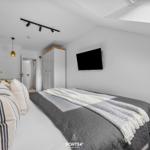 Schlafzimmer mit Bett, Fernseher und Kleiderschrank.