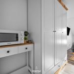 Schlafzimmer mit Dachschräge, Bett, Kleiderschrank und Mikrowelle auf Holzkonsole.