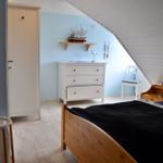 Schlafzimmer mit Dachschrägen, Bett, Schrank und Nachttisch.