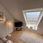 Kleines Zimmer mit Dachfenster, Fernseher und Wandbild an der Wand.