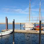 Hafen mit zwei Segelbooten und einem kleinen Boot im Wasser.