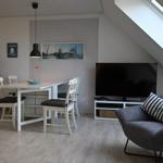 Wohnbereich mit Esstisch, TV und Sessel unter Dachschräge.