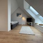 Dachgeschosszimmer mit Schlafcouch, Fernseher und Dachfenster.