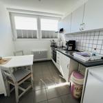 Kitchen with dining area, white cabinets, and windows with blinds.