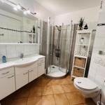 Bathroom with shower, sink and toilet. Tile floor and mirror cabinet.
