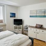 Bedroom with bed, TV, and cabinets. Wall art shows sea.