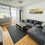 Living room with gray sofa, wooden floor, and balcony view.