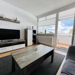 Living room with TV, sofa, and balcony access.