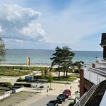 View of beach, park, and sea with playground and parking spots