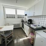 Kitchen with worktop, sink, refrigerator, and dining table with chairs.
