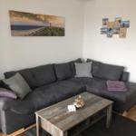 Living room with gray sofa, wooden table, and wall pictures.