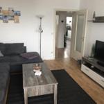 Living room with sofa, coffee table, and TV. Passage to the kitchen.