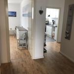 House with kitchen, dining area, and hallway with wooden floor and wall decor.