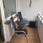 Balcony with table, two chairs, and view of street