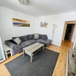 Living room with gray sofa, wooden floor, and wall pictures.