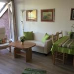 Wohn- und Essbereich mit Sofa, Stuhl, Tisch und Wandbildern.