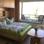 Schlafzimmer mit Bett, Schrank und Balkonansicht.