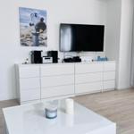 Living room with TV, white cabinets, and glass table.