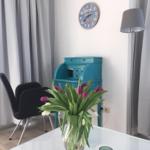 Table with tulips, blue desk, wall clock, and floor lamp