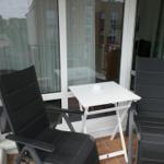 Terrace with two black chairs and a white table.