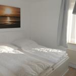 Bedroom with double bed, wall picture, and window with curtains.