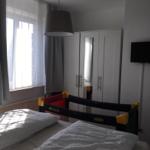 Bedroom with bed, child bed, wardrobe, and window.