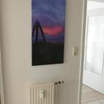 Wall picture with sunset, radiator, and doorway to another room.