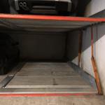 Garage with vehicles and metal floor. Covered parking area.