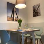 Dining table with chairs, flowers, and wall art on the walls.