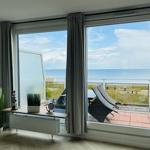 Wohnzimmer mit Meerblick, Balkon und Sitzgelegenheiten.