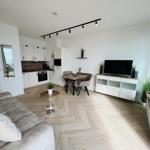 Wohnung mit Küche, Essbereich und TV. Holzboden und moderne Einrichtung.