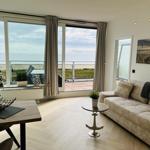 Wohnzimmer mit Meerblick, Sofa, Tisch und Balkon.