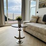 Wohnzimmer mit Sofa, Tisch und Blick auf Balkon.