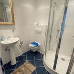 Badezimmer mit Dusche, Toilette und Waschbecken mit Spiegel.