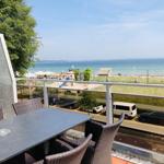 Terrasse mit Tisch und Stühlen bietet Blick auf Strand und See.