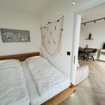 Schlafzimmer mit Doppelbett und Blick in Wohnbereich mit Esstisch.