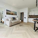 Wohnung mit Wohn- und Essbereich, Küche und Schlafzimmer. Holzfußboden und helle Wände.